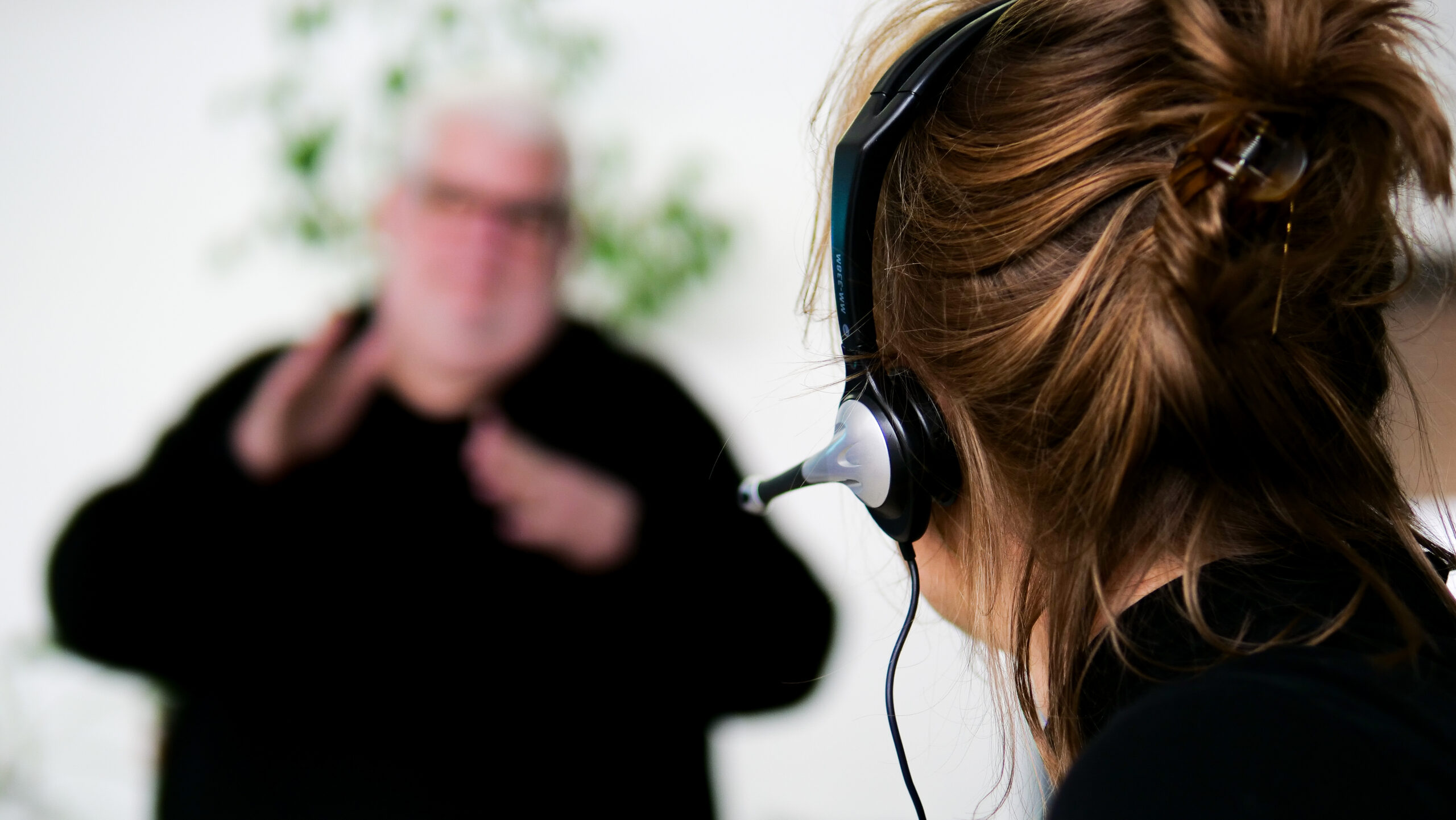 Zwei Mitarbeiter*innen von der yomma GmbH im Studio und Hamburg. Sie zeigen eine Situation Dolmetschen, Beraten, Textredaktion für BITV 2.0 Webseitentexten, Gebärdensprachvideo, Gebärdensprachfilme