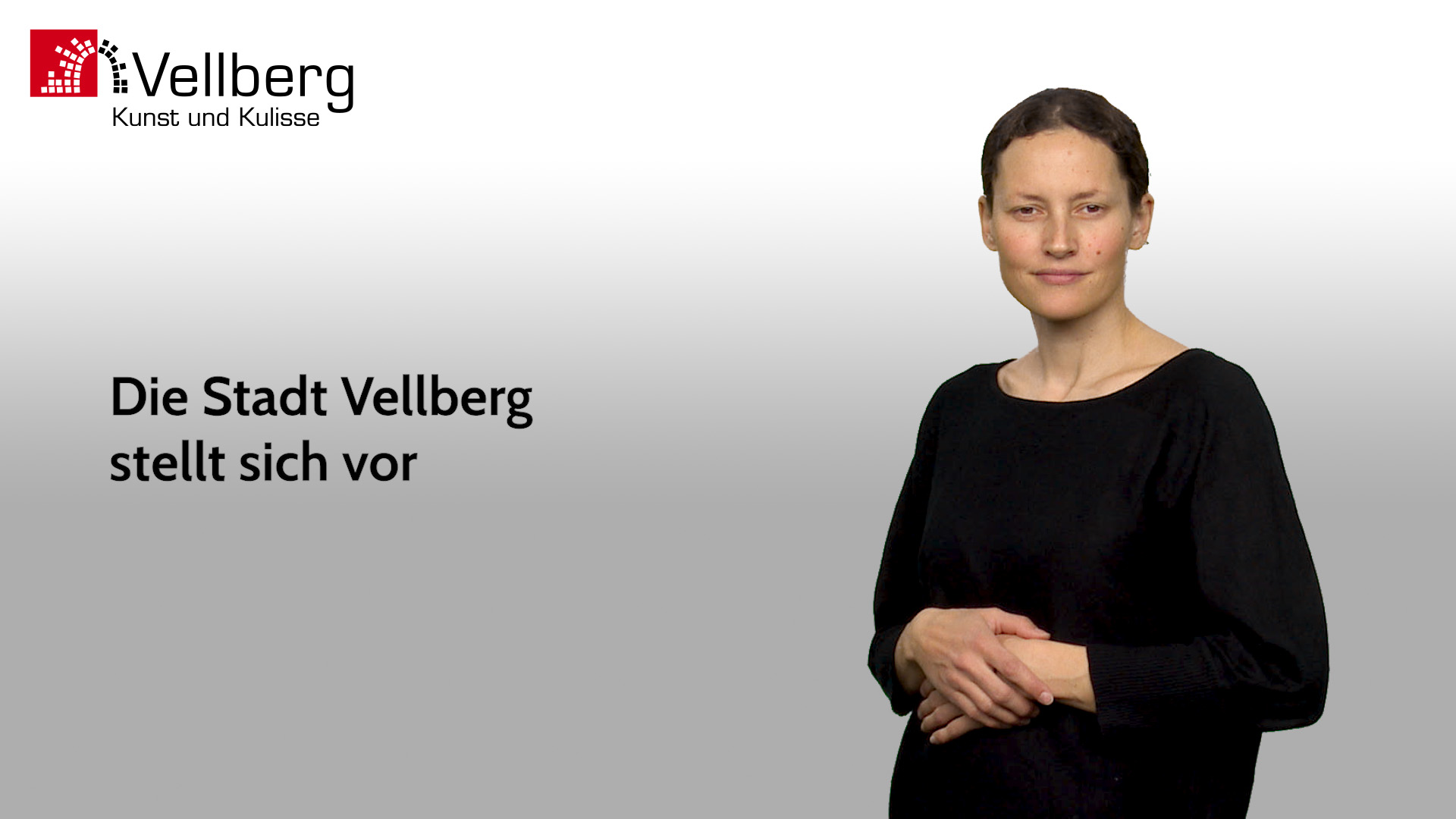 Gebärdensprachvideo der Stadt Vellberg: Eine Gebärdensprachdolmetscherin steht vor hellem Hintergrund und stellt Inhalte zur Stadt Vellberg vor. Logo ‚Vellberg‘ sowie der Text ‚Die Stadt Vellberg stellt sich vor‘ sind eingeblendet.