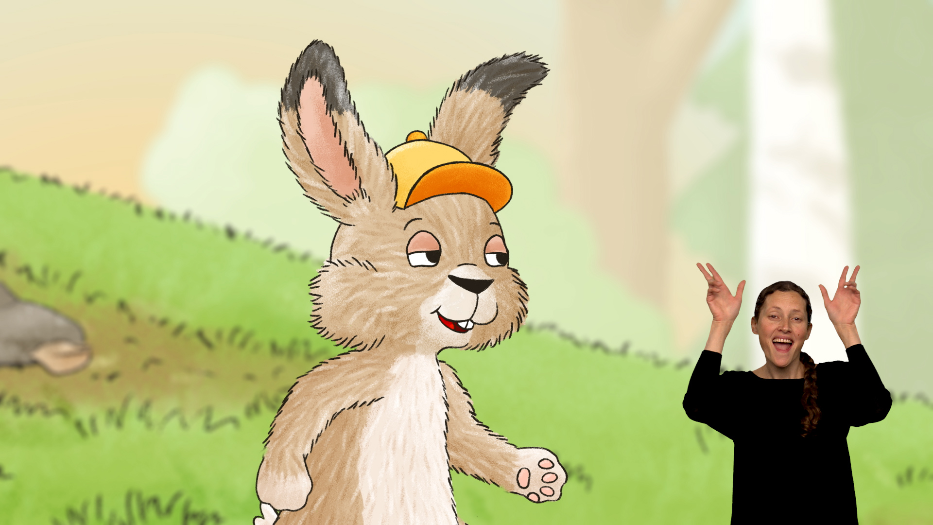 Gebärdensprachvideo als Film-in-Film-Produktion: Eine Gebärdensprachdolmetscherin ist rechts im Bild eingeblendet und gebärdet. Im Hintergrund ist eine gezeichnete Hasenfigur mit Kappe in einer Landschaft zu sehen. Darstellung von Deaf Performance.